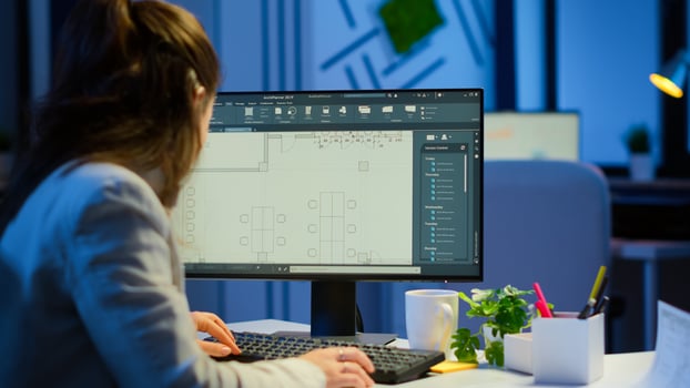 Over the shoulder shot of engineer working with architectural plans, cad software on desktop computer. Designer using arhitecture blueprints of buildings working overtime, creating and studying photo