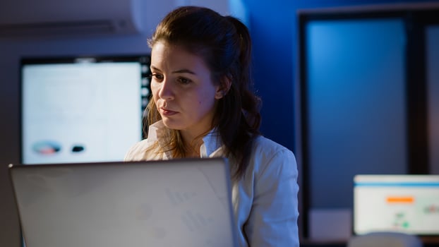 Freelancer typing on laptop late at night standing in start up business office late at night working. Busy focused employee using modern technology network wireless doing overtime for job searching photo