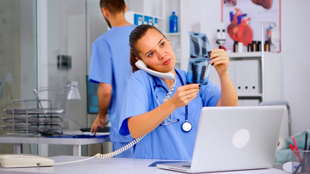 Physician nurse answering patient call by phone, looking at his radiographys, mri scan. Healthcare physician in medicine uniform, receptionist doctor assistant helping with phone concultation photo