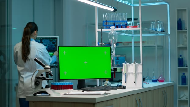Computer with green screen working in labooratory with mock up monitor, chroma key display while professional engineer testing virus evolution in background. High tech development lab. photo