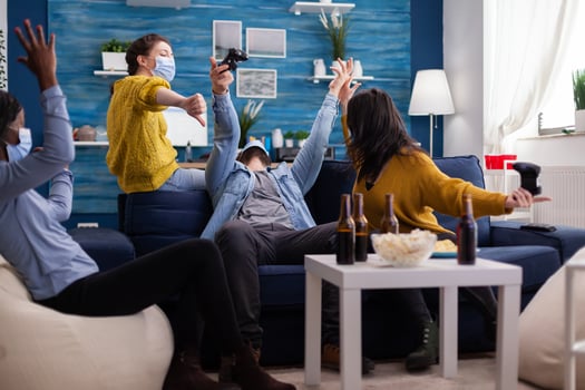 Disappointed group of mixed race friends after losing game competition while playing sitting on couch in living room keeping social distancing as prevention during coronavirus outbreak. photo