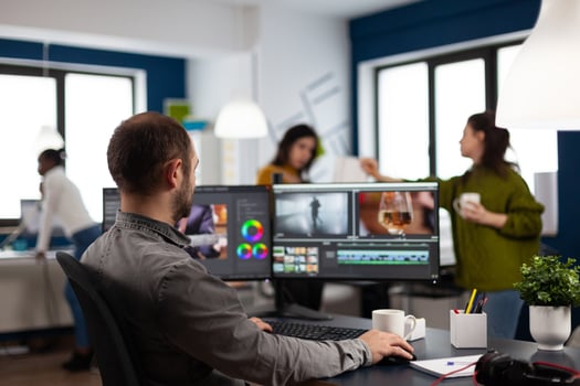 editor cuting footage working at film editing montage on computer with dual monitors setup in multimedia creative agency office. Videographer man processing film using post production software photo