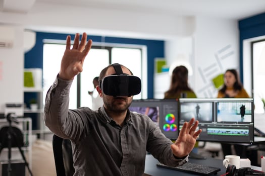 editor experiencing virtual reality headset, gesturing, editing film montage using post production software working in creative company office. Videographer using VR headset in multimedia agency photo
