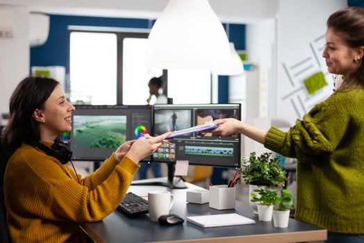 Creators drinking coffee and talking during office break sitting at desk in digital agency studio. editor and sound engineer working at movie project, editing film footage in software app photo