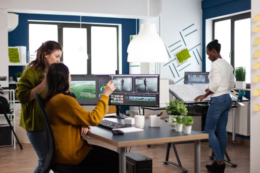Coworkers talking about movie project looking at film footage working in creative start up agency office with two monitors. Videographers processing montage with post production software photo
