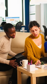 Start up team meeting with company leader pointing at strategy on financial reports. Team work in modern office of diverse international colleagues group sitting on couch at table in startup management photo