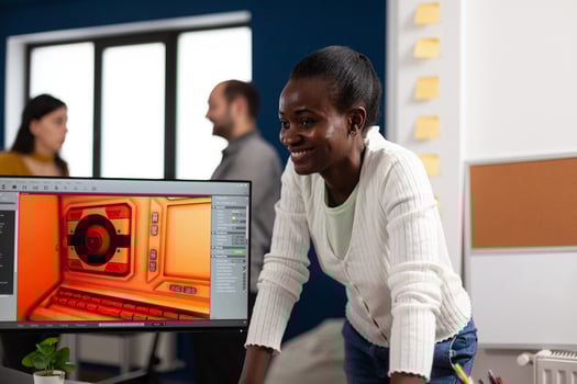 Multiethnic women designer looking at computer with dual displays working together at gaming project in company office. Gamer workers developing new games application on pc with modern technology photo