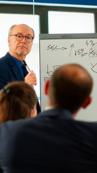 Confident man business coach giving flipchart presentation training diverse workers group at workshop, businessman presenter leader mentor explaining graph teaching team employees at corporate meeting photo