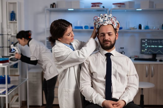 Specialist physician woman putting eeg headset on man patient monitoring brain evolution analyzing nervous system activity in clinical laboratory. Doctor in neuroscience doing medical tomography photo