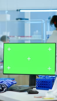 Medical research scientist working on pc with green screen mock up template in applied science laboratory. Engineers conducting experiments in background, examining vaccine evolution using high tech photo