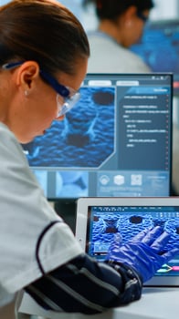 Scientist using digital tablet working in modern medical research laboratory, analyzing DNA information. Medicine, biotechnology research in advanced pharma lab, examining virus evolution photo