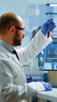 Scientist man examining blood samples and liquid working in modern equipped laboratory. Team of doctors analysing vaccine evolution using high tech researching diagnosis against covid19 photo
