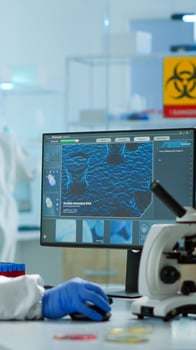 Chemist in ppe suit typing on pc checking vaccine development in modern equipped laboratory. Doctor working with various bacteria, tissue and blood samples, pharmaceutical research for antibiotics photo