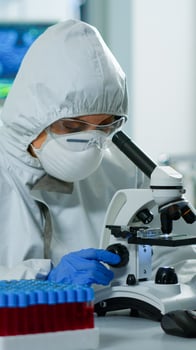 Woman scientist in ppe suit working in lab using modern microscope with slides. Team of chemists researcher examining virus evolution using high tech for vaccine scientific research against covid19 photo