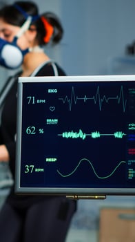 Monitor showing EKG scan of athlete running on cross trainer and medical specialists supervise exercise in background, controlling physical activity, measuring heart rate in sports science laboratory photo