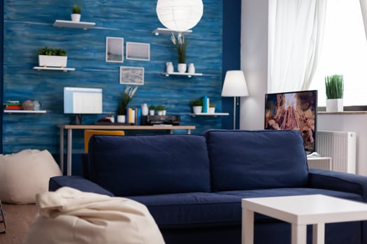 Empty modern living room with no people having wallcomfortable couch, elegant style with work place in background and television. Interior with nobody in with blue walls, beautiful decorated apartment photo