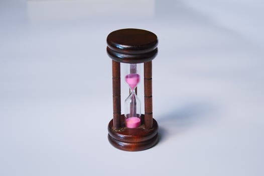 Hourglass with a wooden body and pink sand photo