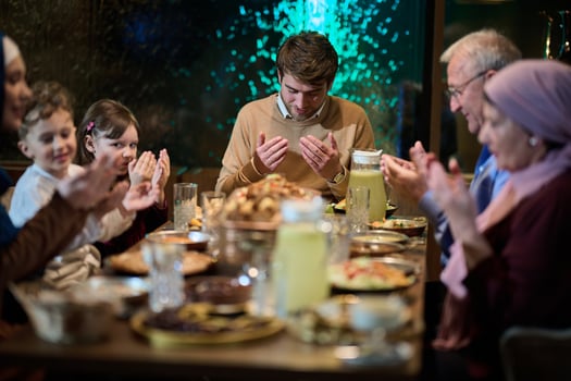 In a modern restaurant setting, a European Islamic family comes together for iftar during Ramadan, engaging in prayer before the meal, uniting tradition and contemporary practices in a celebration of photo