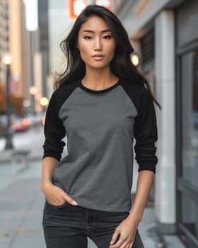 A woman wearing a gray and black raglan shirt stands on a city street photo