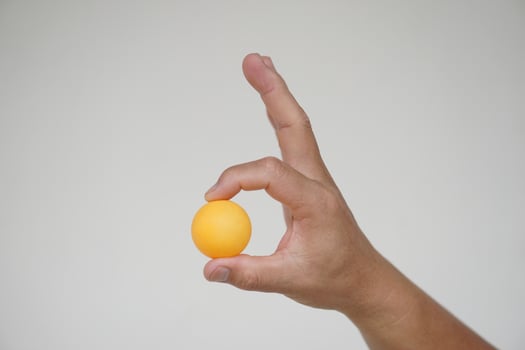 Hand holding orange table tennis ball or Ping pong ball, isolated on white background. concept, sport equipment. Exercise and workout tool. Competitive game sport. photo