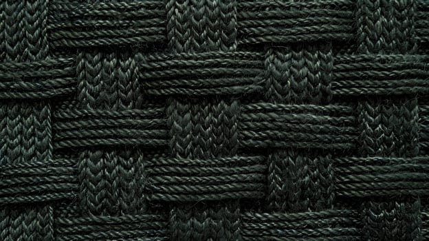 A dark forest green wool with an intricate woven texture resembles a geometric maze of crisscrossing lines and raised loops photo