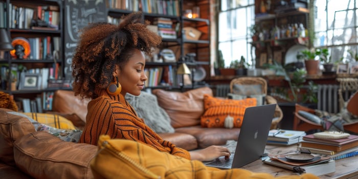 A woman is at ease on a couch, engrossed in her laptop photo