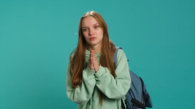 Woman doing begging hand gesture, in ardent need of favor from friend, isolated over studio background. Young girl doing please gesturing, requesting assistance, camera A photo