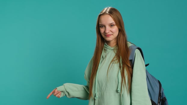 Portrait of cheerful person pointing finger towards empty space, doing advertising. Happy lady doing presentation, showing copy text, isolated over studio background, camera A photo