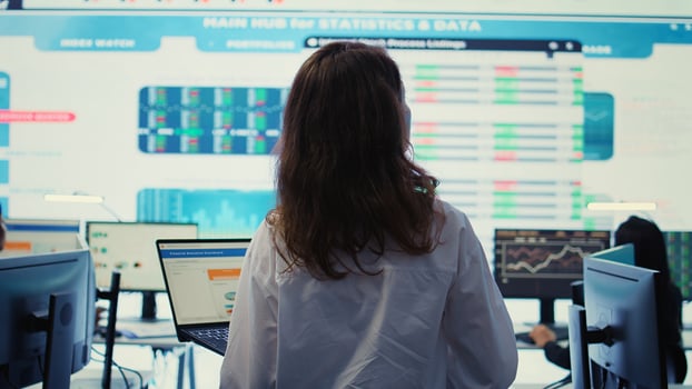 Project leader conducting a market research with a big screen in company headquarters office, ensuring enterprise progress. Financial manager studying the current organizational situation. Camera B. photo