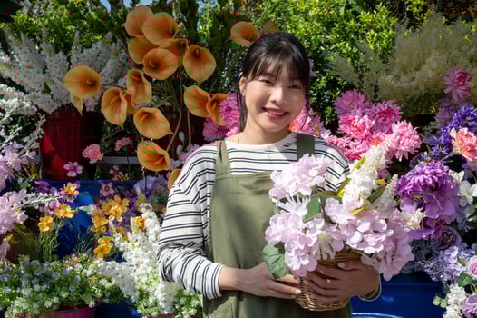 An attractive Asian female florist with a beautiful bouquet in front of her flower shop. photo