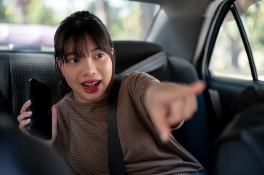 A happy young Asian female passenger is giving directions to a taxi driver. photo