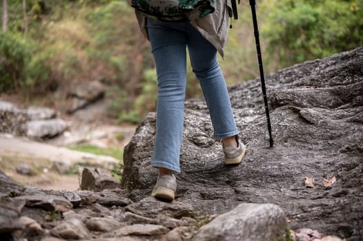 Close-up legs image of a woman is hiking with a trekking pole on the rock mountain. photo