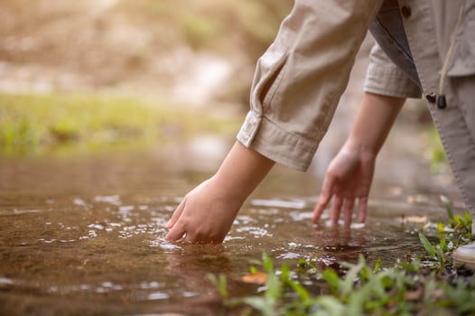 Close-up hand image of a woman touching the water in a small nature canal waterfall on the mountain photo