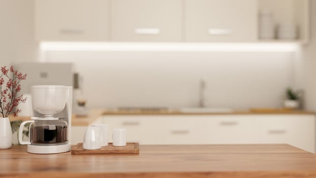 A copy space on a wooden kitchen tabletop with an espresso machine in a modern white kitchen. photo