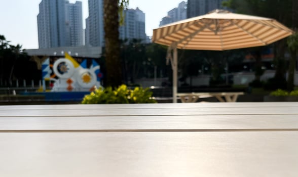 Close up selective focus on outdoor wooden table surface isolated on urban city buildings, trees, and umbrella on horizontal ratio background photography. photo