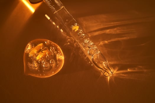 Pipette with serum shimmering in the sun on a beige background. photo