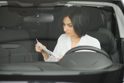 Young woman smiling in her new car in a showroom photo