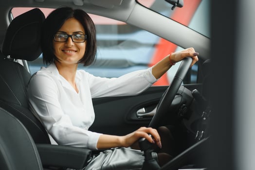 Photo of happy young woman sitting inside her new car. Concept for car rental