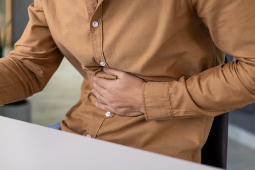 Close-up of person holding their stomach, experiencing pain and discomfort. Represents stomach ache, indigestion, or other abdominal issues. photo