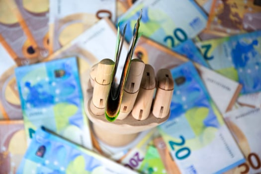 A wooden hand holds a stack of twenty Euro banknotes against a backdrop of additional twenty Euro notes photo
