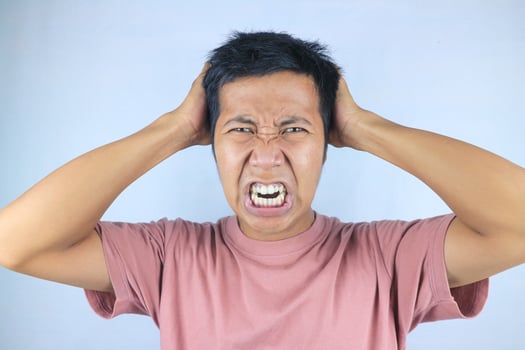 Stressed facial expression of young asian man while clutching head, isolated on white background photo