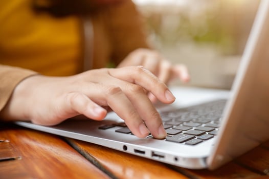 A close-up image of a woman working remotely, working on her laptop, typing on the keyboard. photo