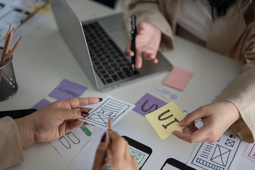 A meeting table with a team of creative UI UX graphic designers working on a mobile app prototype. photo