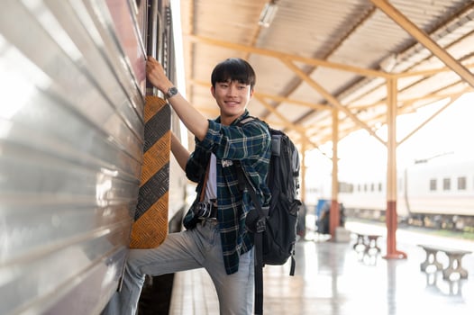 A happy Asian man backpacker is getting on the train, travel somewhere on his summer vacation. photo
