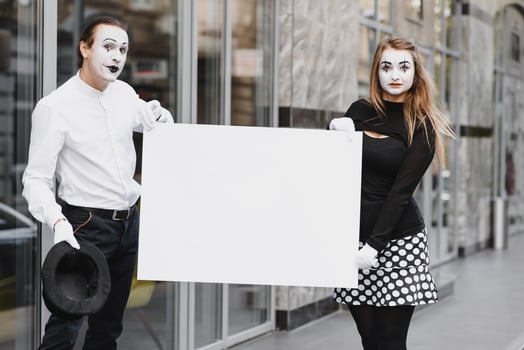 Your text here. Actors mimes holding empty white letter. Colorful portrait with gray background. April fools day photo