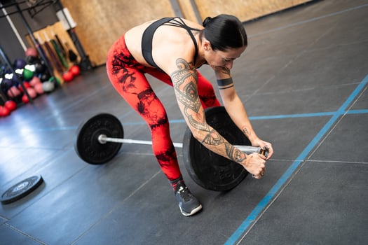 Woman preparing a bar with weights to weightlifting photo