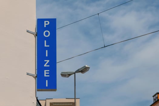 blue police sign mounted on building wall in germany with the word polizei photo