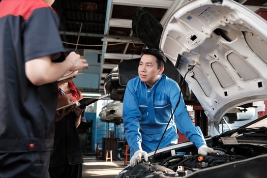 Asian male professional automotive engineer supervisor describes car engine maintenance and repair work with mechanic worker staffs team in fix service garage, specialist occupations in auto industry. photo
