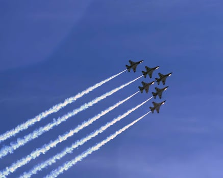 Airshow of military jet fighters. Group of military airplanes performs maneuvers with a smoke trace. Aviation background photo