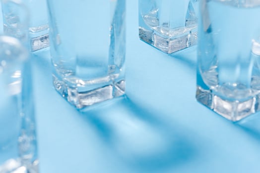 Glasses of water on blue. Close up. Copy space. Water balance for healthy and detox. photo